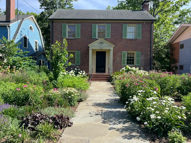Front of the house with full summer planting beds in bloom
