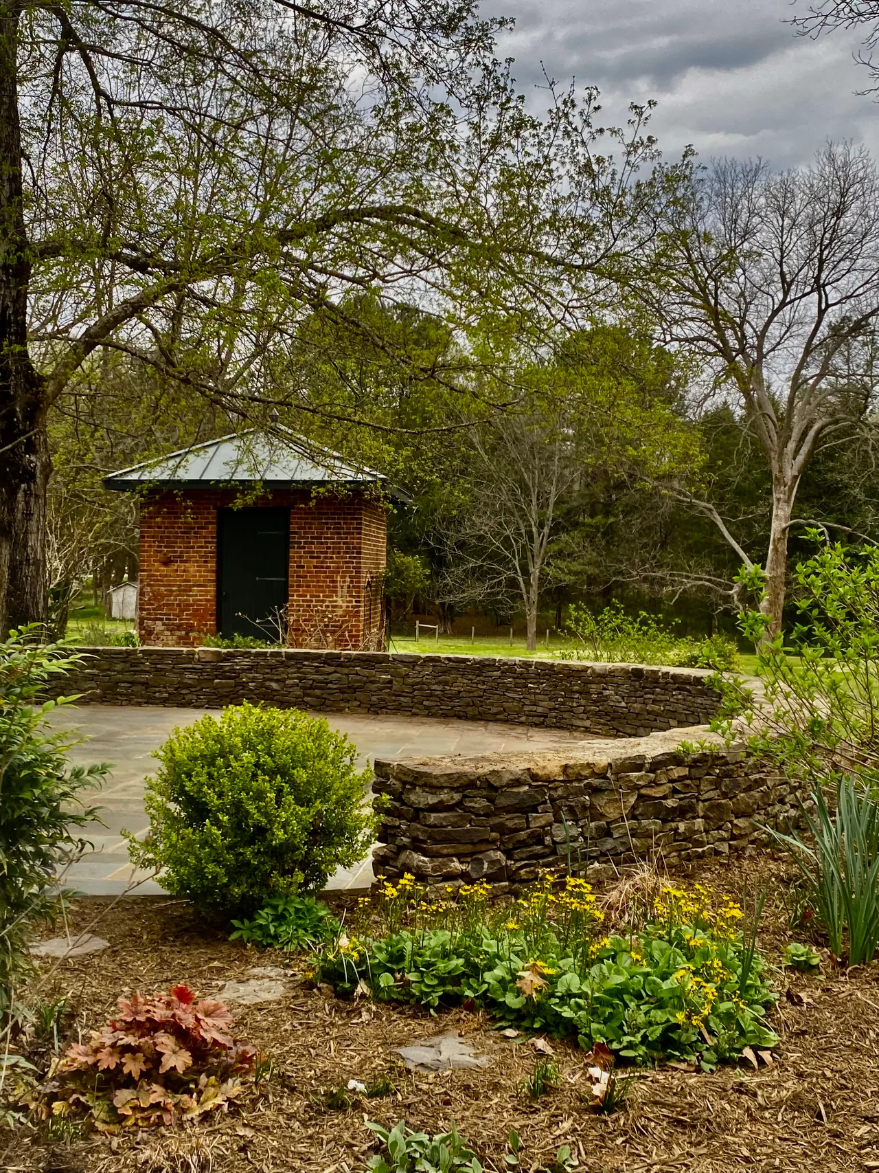 Dry-stack stone wall and flagstone patio by the brick outbuilding