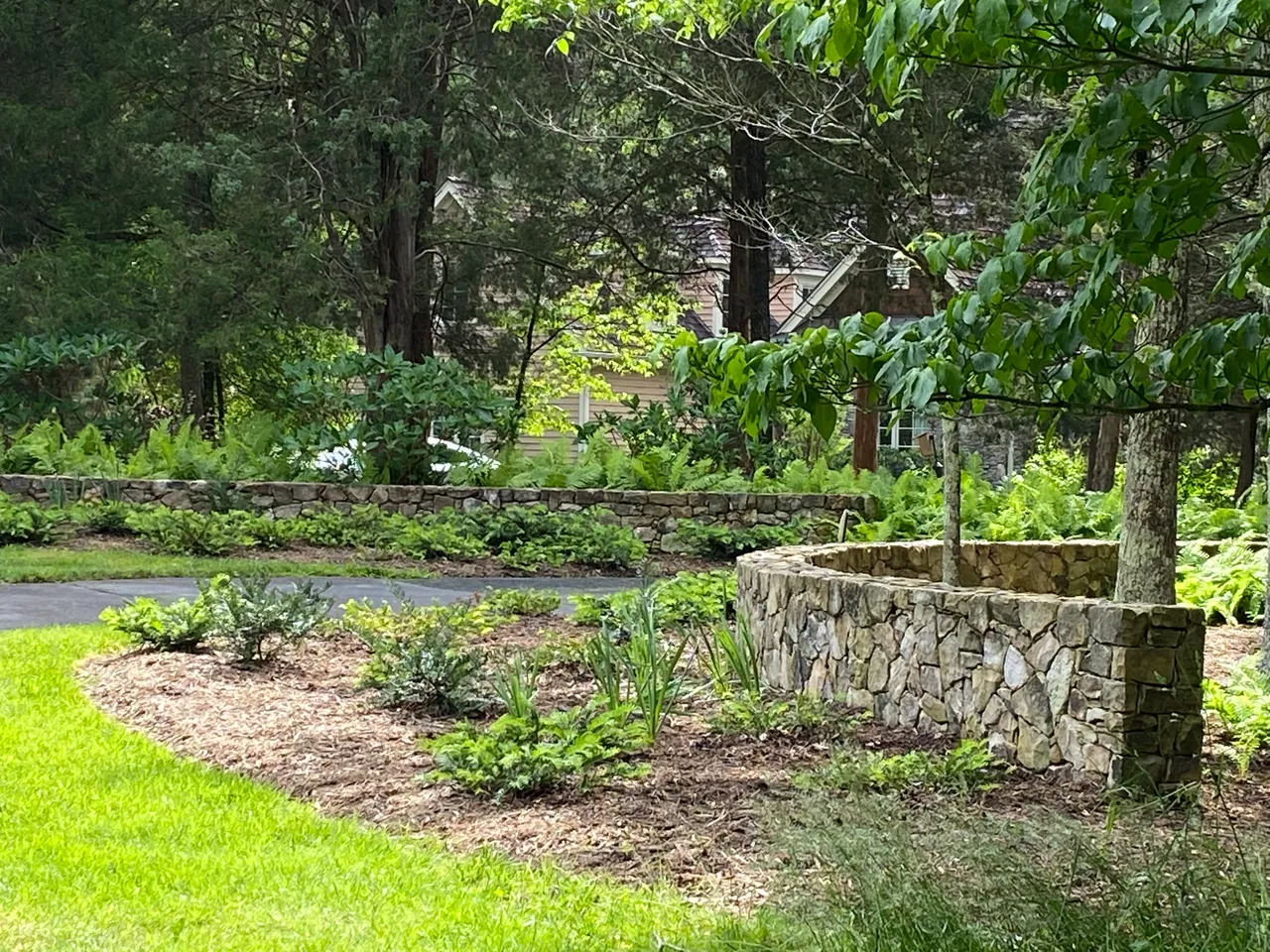 Curved stone planter and long wall along the driveway, wide view